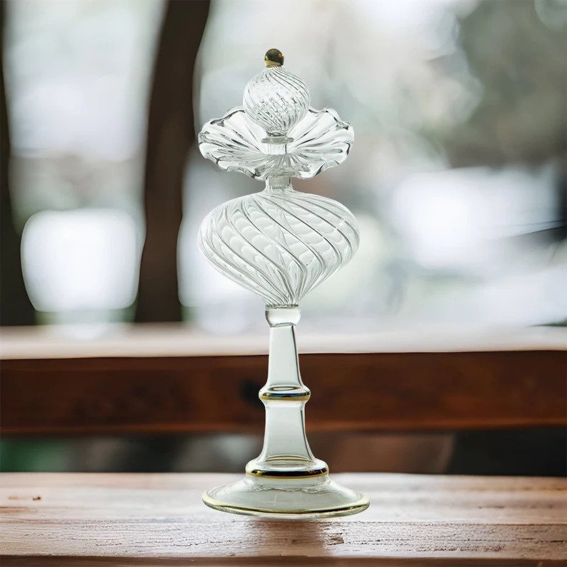 Clear Ribbed perfume bottle with stopper on wooden shelf | Les Trois pyramides