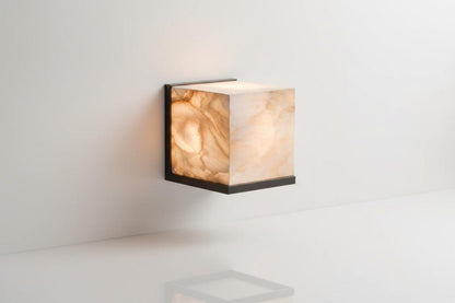 Square wall light with marble-like finish on a white wall