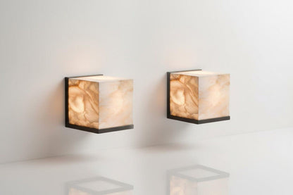 Two square wall lights with marble-like finish on a white wall.