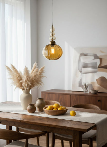 Decorative pendant light with a yellow glass shade on a neutral background