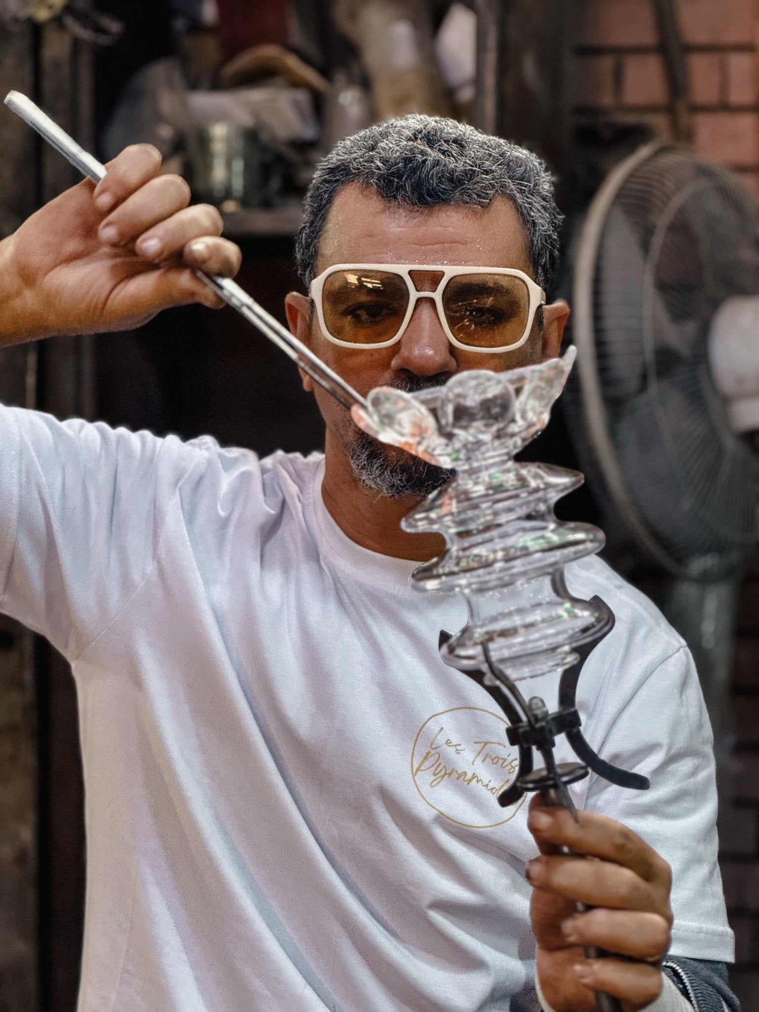 Artisan holding hand-blown glass flower shade in workshop for wall light