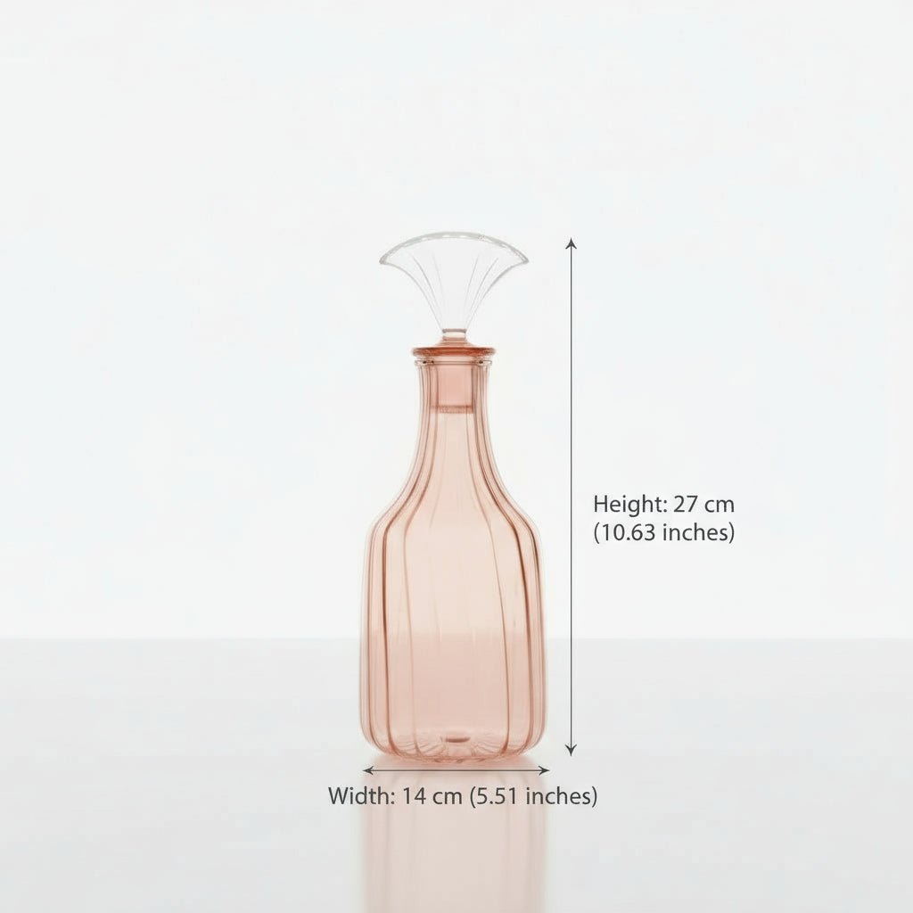 Pink glass decanter with a wine glass and flowers on a marble surface.