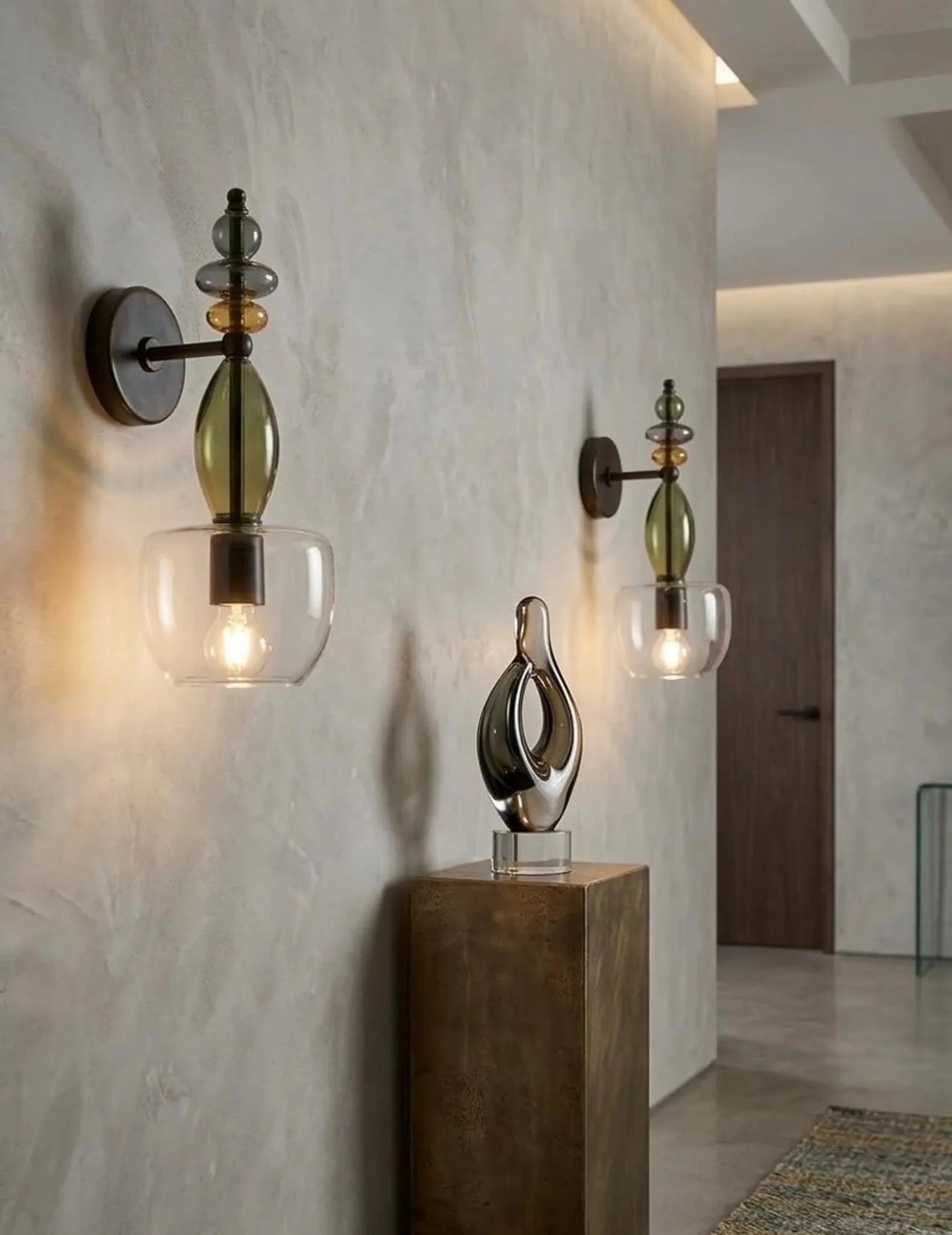 Decorative wall sconces with glass shades on a textured wall.