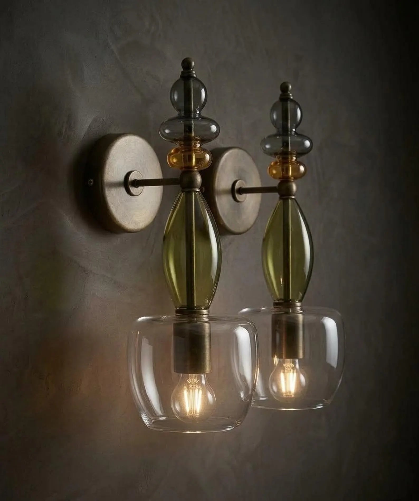 Decorative wall sconce with glass shades and metal accents on a dark background