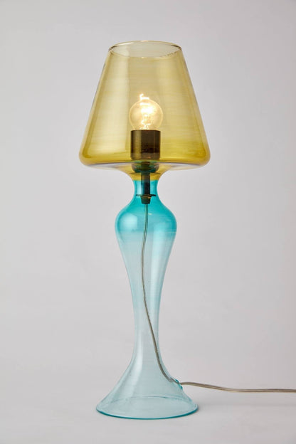 Table lamp with a yellow glass shade and blue base on a light gray background