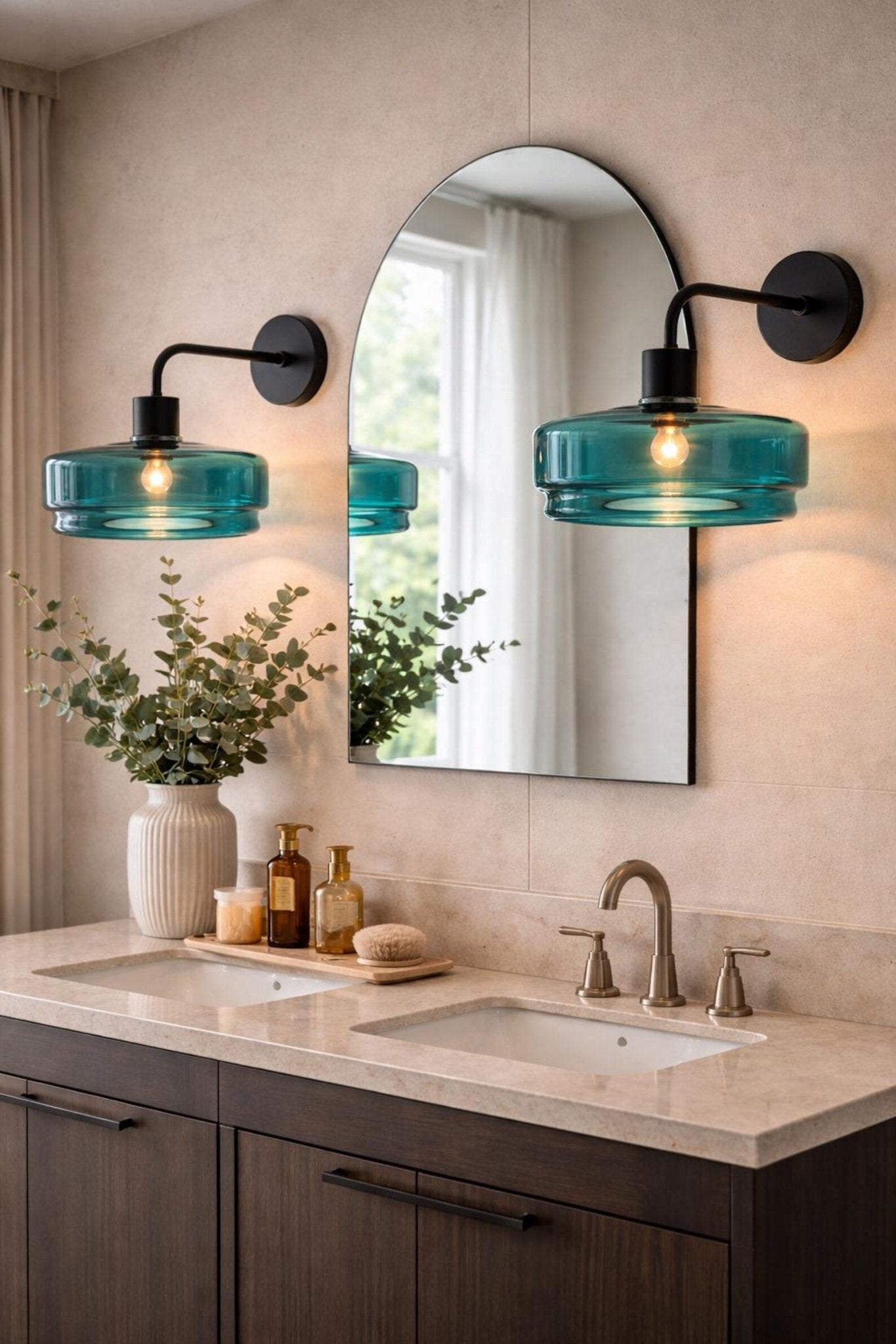 Bathroom vanity with teal glass sconces, mirror, and decorative items.
