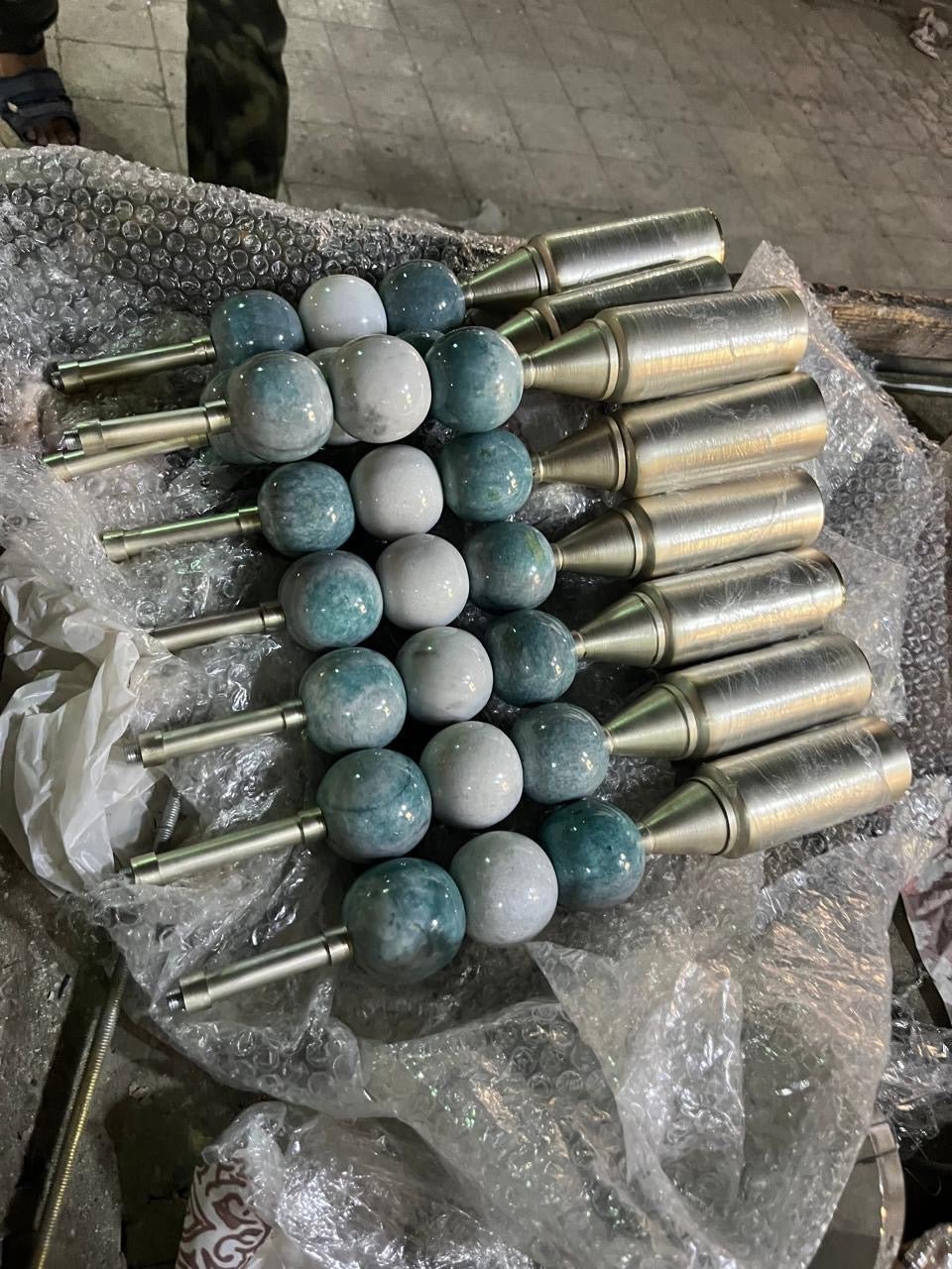 Artisan crafting a handmade wall sconce with natural jade stones and glass globe in workshop | Les Trois Pyramides