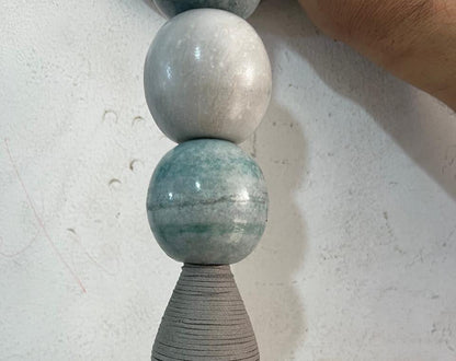 Artisan crafting a handmade wall sconce with natural jade stones and glass globe in workshop | Les Trois Pyramides