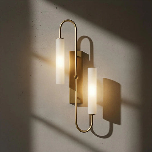 Modern wall sconce with gold fixture and white glass on a textured wall.