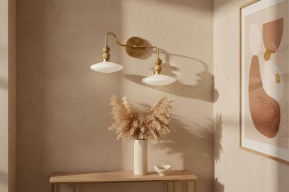 Decorative wall sconce, vase with dried plants, and abstract art on a beige wall.