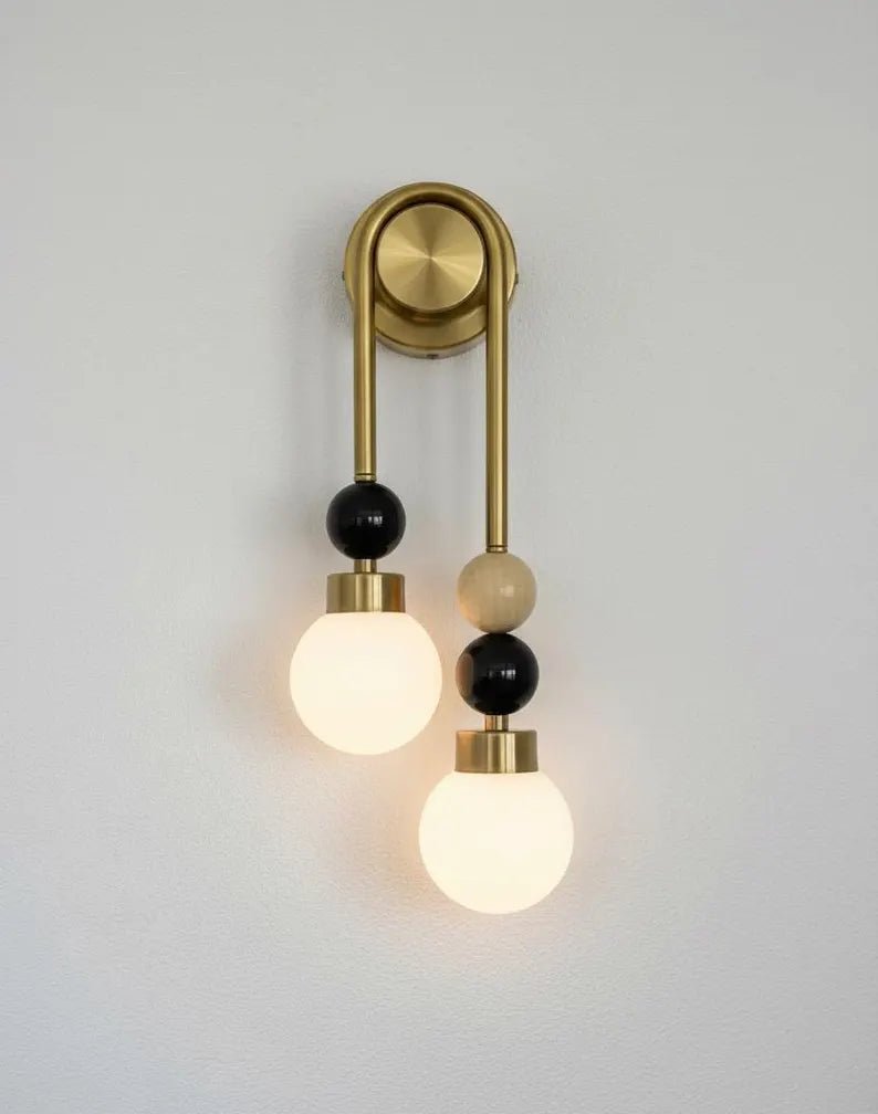 Close-up of handmade brass wall sconce showing natural onyx stone and frosted glass globe
