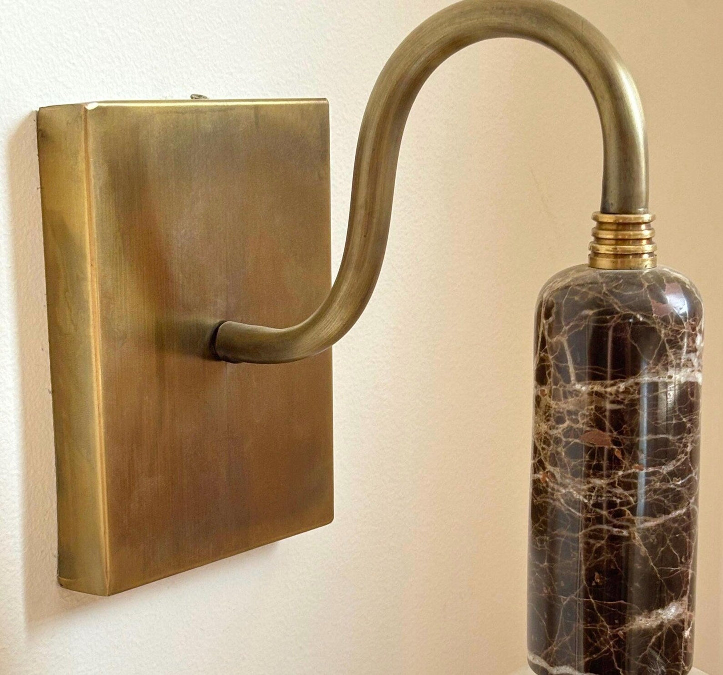 Brass wall-mounted fixture with marble-textured bottle .