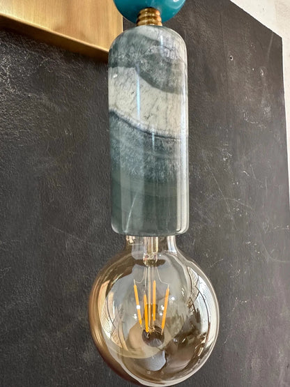 Decorative wall light fixture with a glass shade and exposed bulb on a dark background