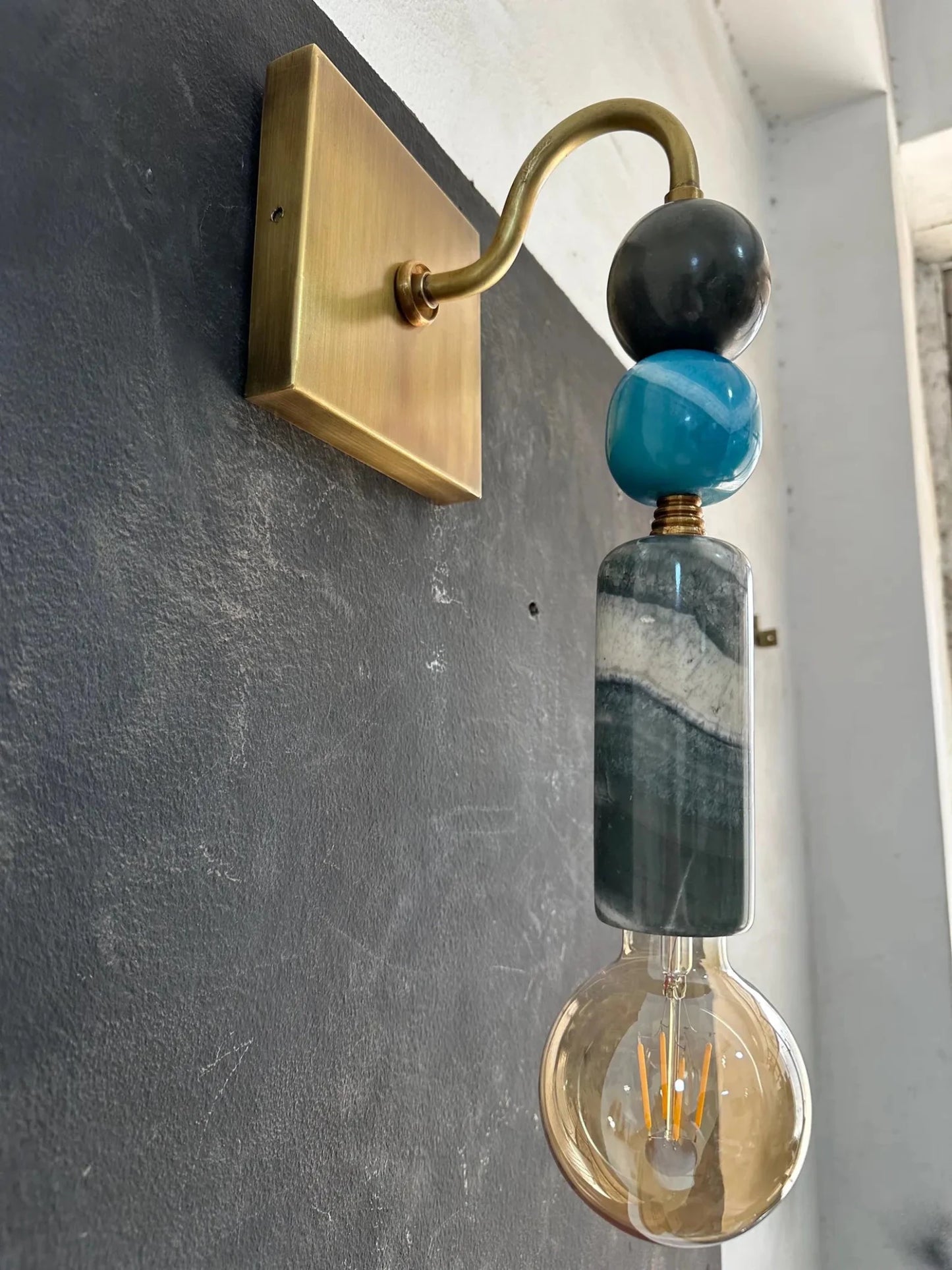 Wall-mounted light fixture with decorative beads on a gray wall