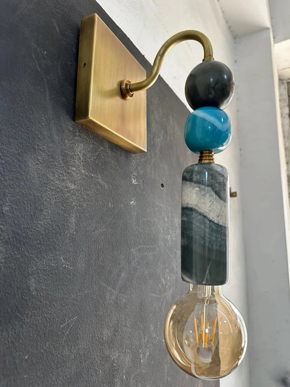 Wall-mounted light fixture with decorative beads on a gray wall