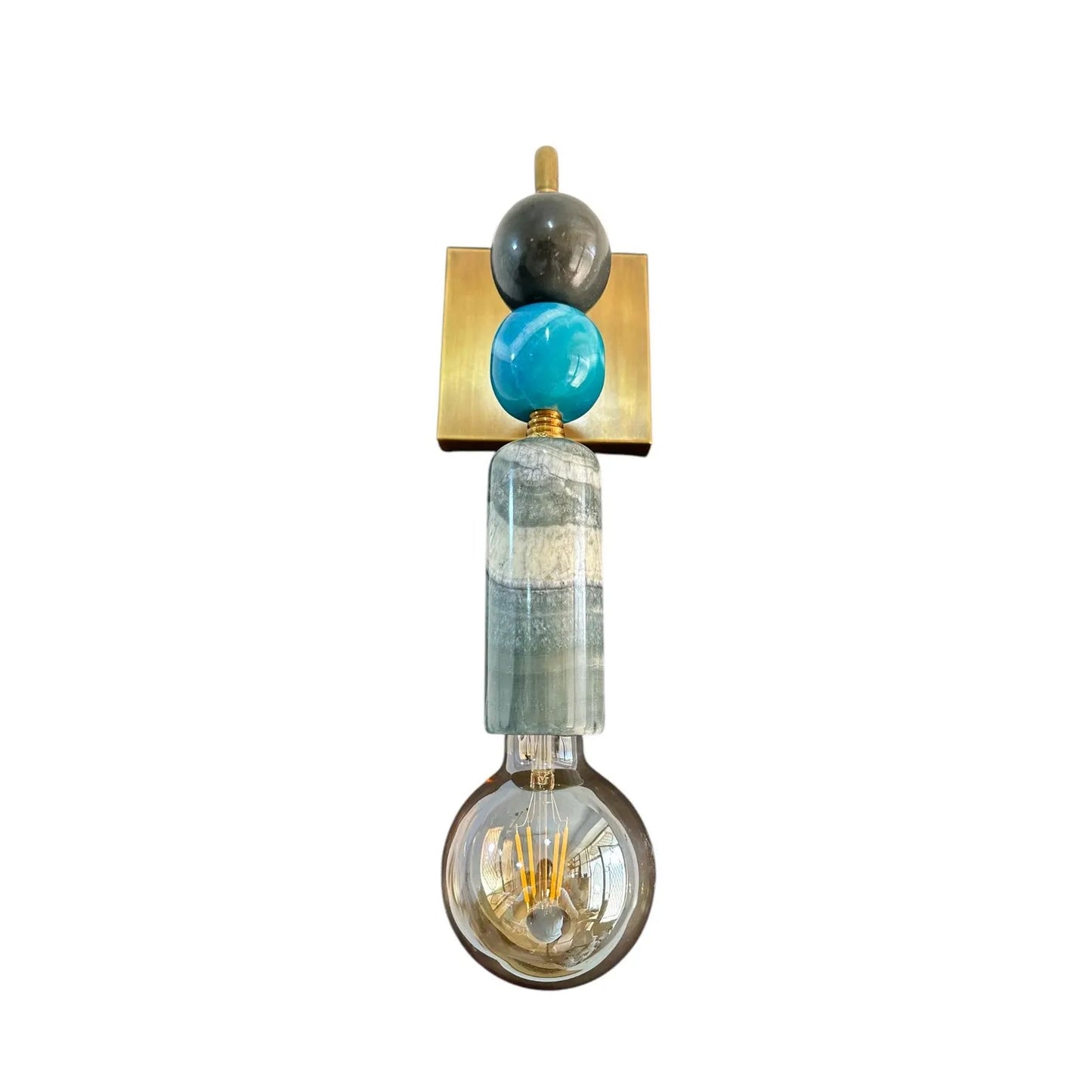 Decorative wall light fixture with a gold square base, turquoise sphere, and clear glass shade on a white background.