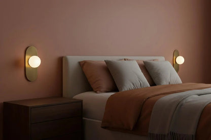 Bedroom with a bed, nightstands, and wall lights on a pink wall.
