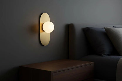 Modern wall sconce on a dark wall next to a bed