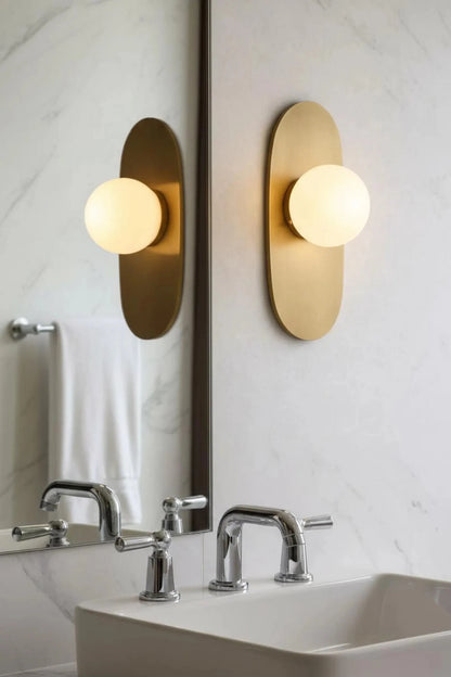 Bathroom with gold wall sconces reflecting in a mirror.