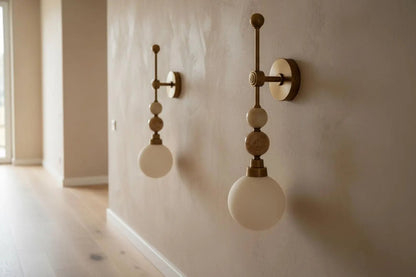 Two wall-mounted lights with spherical bulbs on a beige wall.