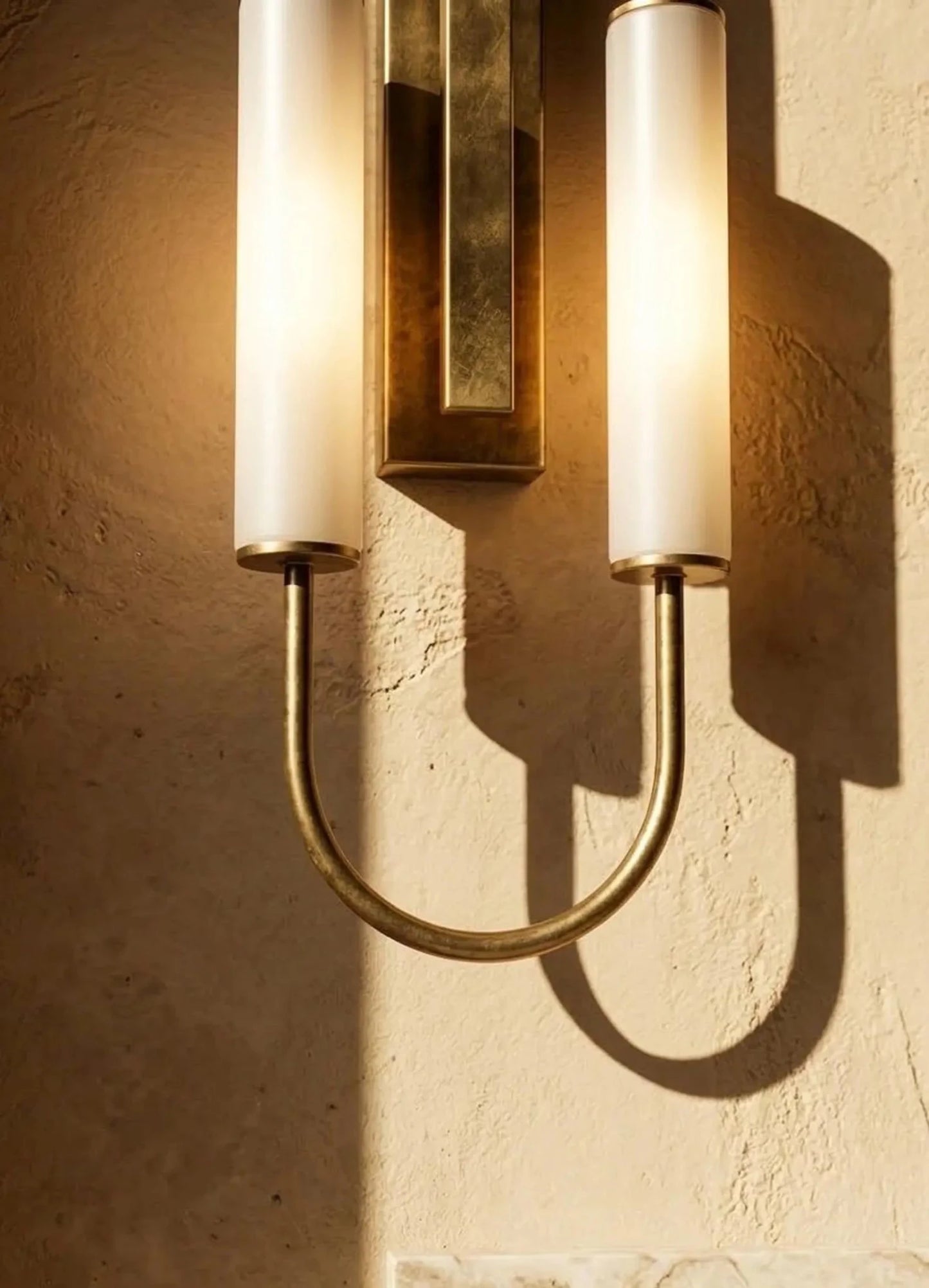 Wall-mounted light fixture with gold accents on a textured wall.