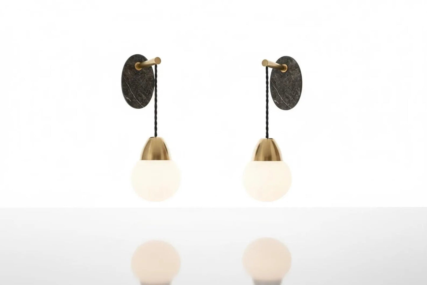 Two wall-mounted light fixtures with round glass shades on a white background