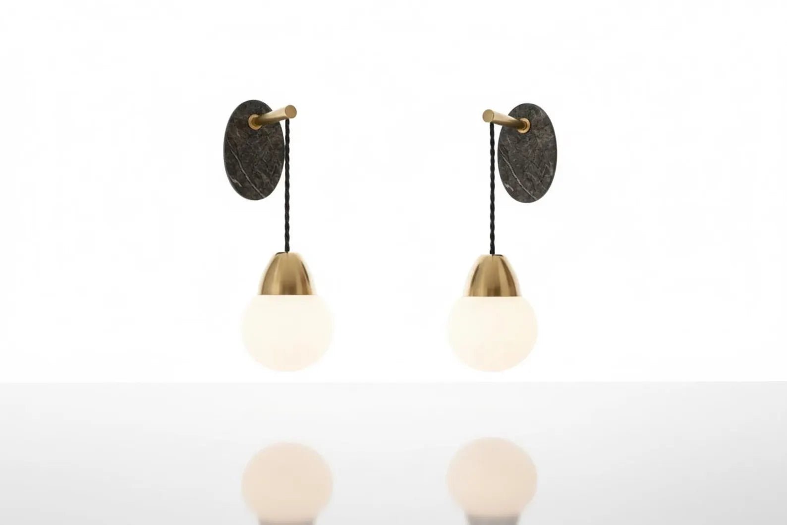 Two wall-mounted light fixtures with round glass shades on a white background