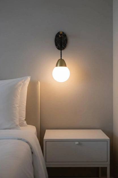 Wall-mounted light fixture on a neutral wall above a bed with white bedding.