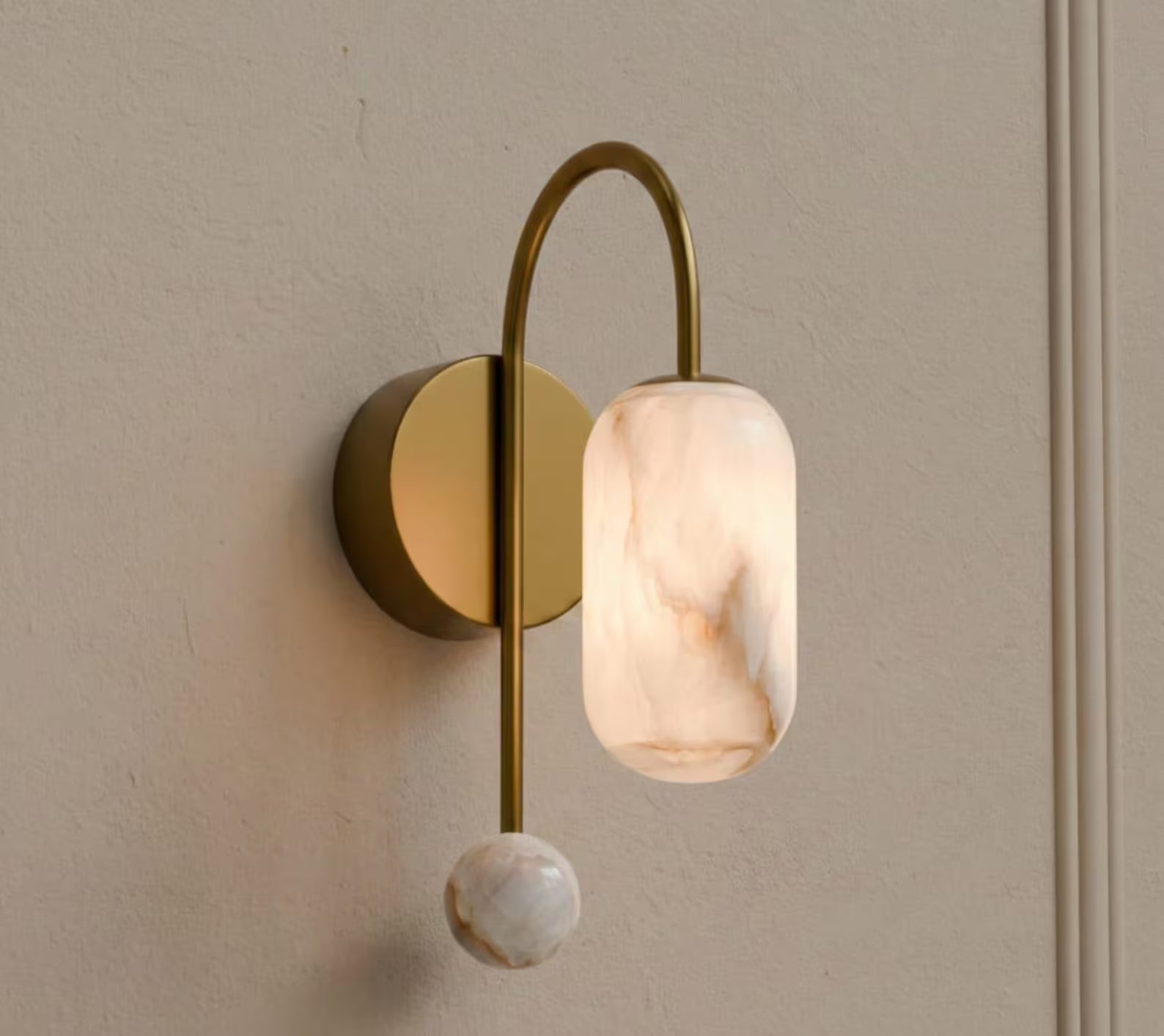 Wall-mounted light fixture with marble-like glass shade on a neutral wall.