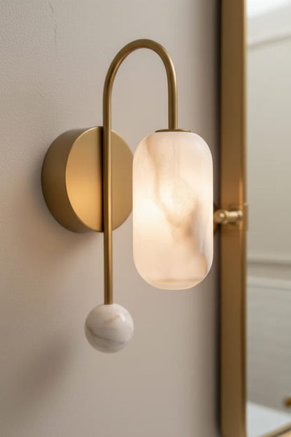 Modern wall lamp with gold fixture and marble-like shade on a neutral wall.