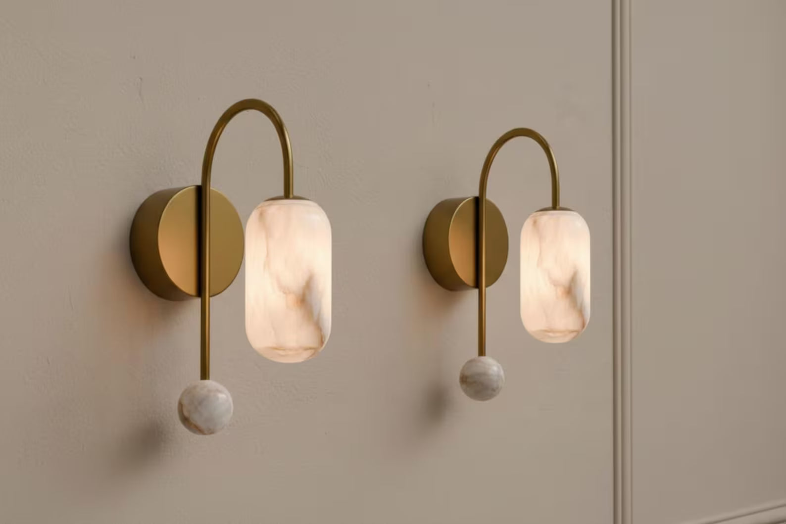Two wall-mounted lights with gold fixtures and marble-like shades on a neutral wall.