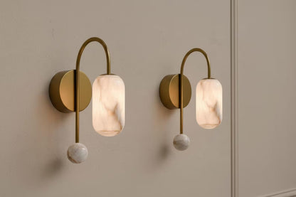 Two wall-mounted lights with gold fixtures and marble-like shades on a neutral wall.