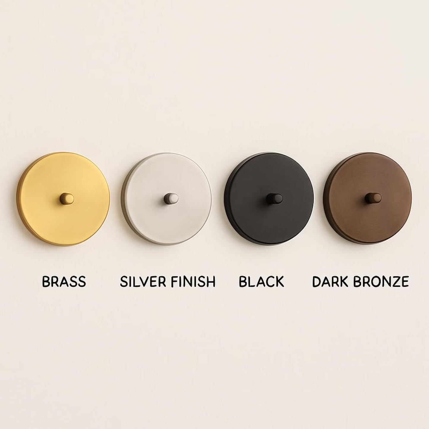 Four circular door handles in brass, silver finish, black, and dark bronze on a beige background.