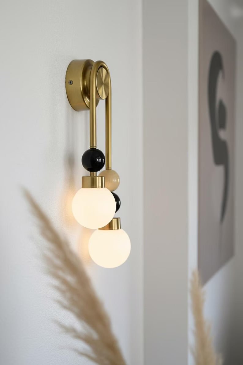 Handmade double brass wall light with natural onyx stone details and frosted glass globes mounted on wall
