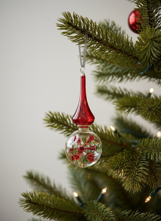 Decorative Christmas ornament with red top and floral design on a tree branch.