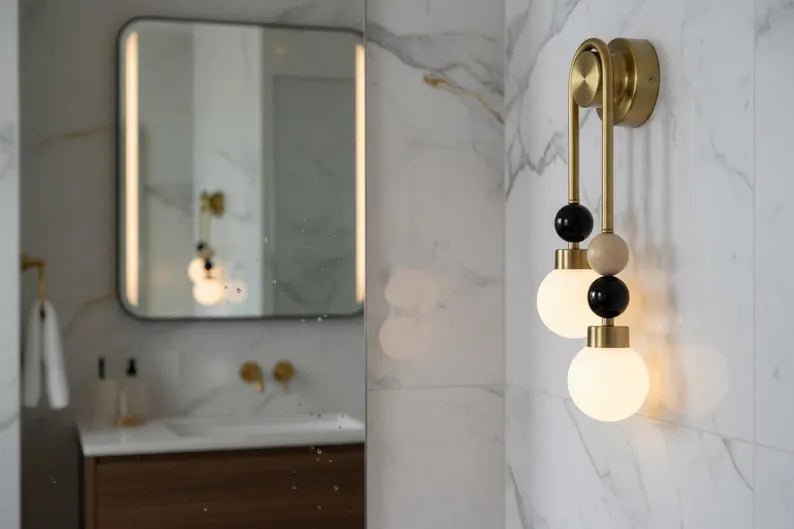 Double brass wall light with onyx stone details installed above bathroom mirror with frosted glass globes
