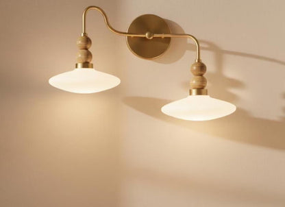Double wall sconce with gold arm and wooden knobs on a beige wall.