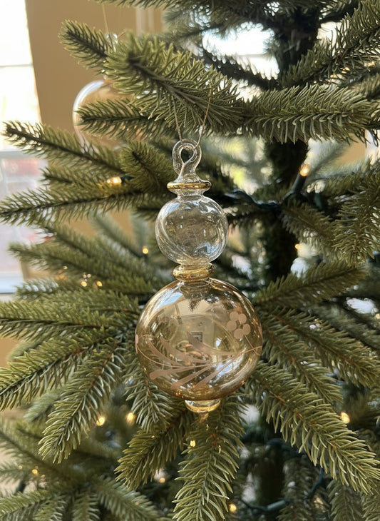Hand holding a decorative glass ornament with a blurred indoor background