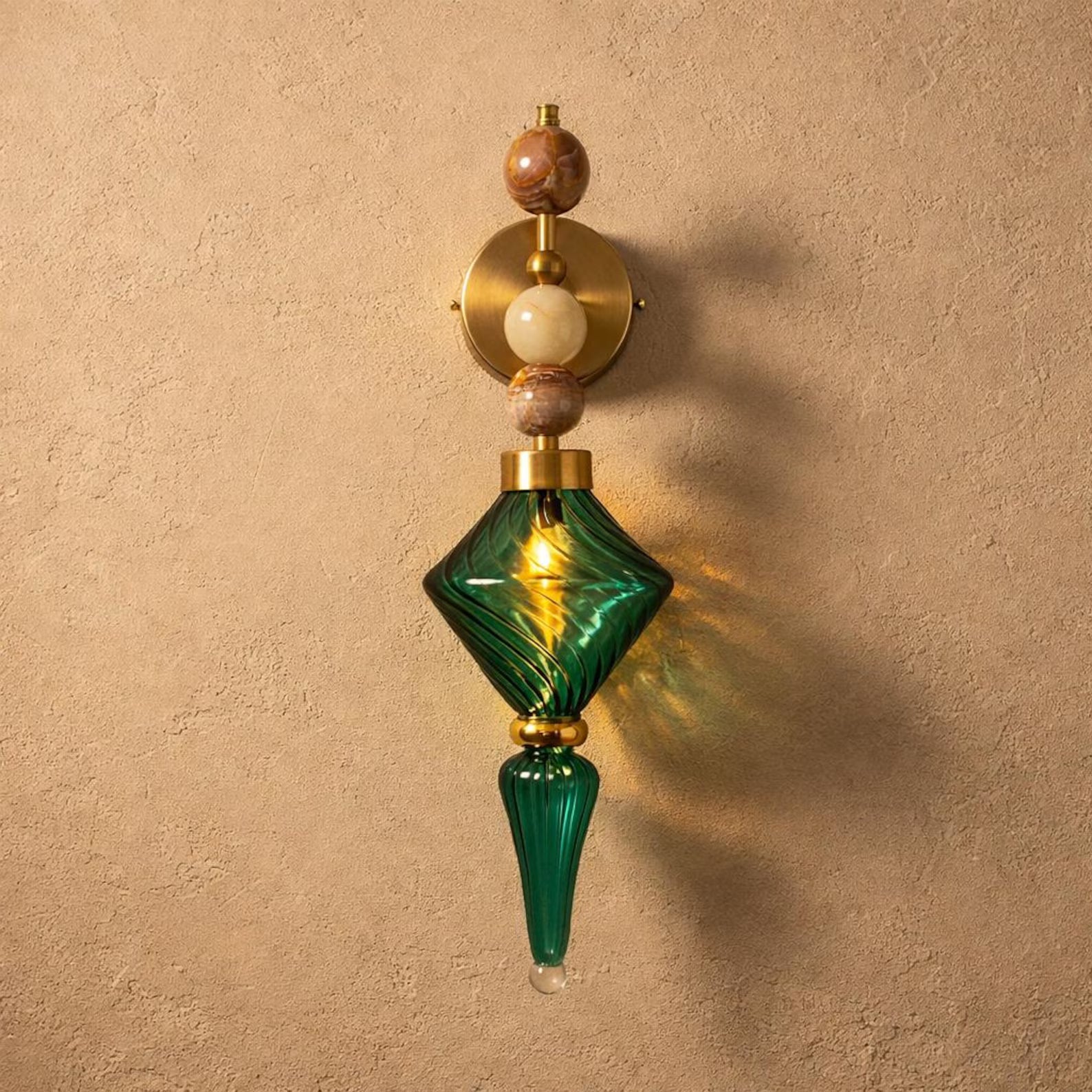 Decorative wall sconce with green glass and wooden accents on a beige wall.
