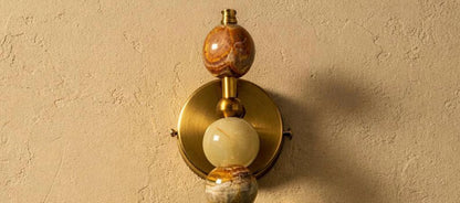 Decorative wall sconce with a marble-like finish on a beige wall.