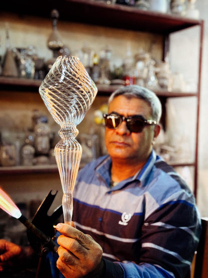 Man working with glassblowing tools in a workshop setting