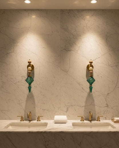 Bathroom vanity with dual sinks, gold fixtures, and decorative wall sconces against a marble wall.