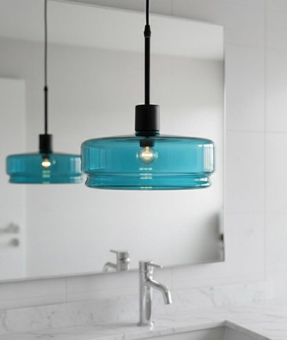Turquoise pendant lights hanging above a bathroom vanity with a mirror.