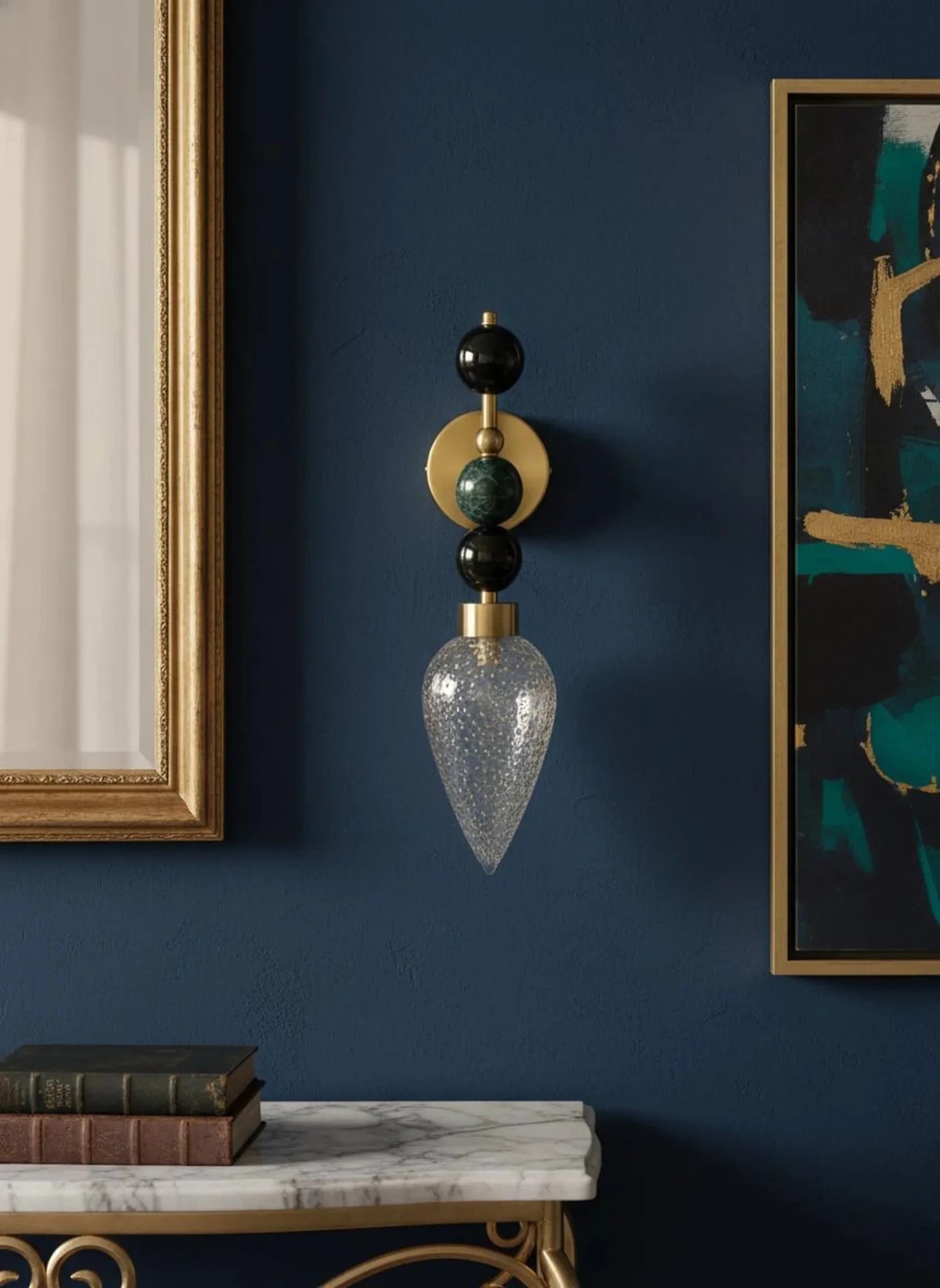 Decorative wall sconce with black, gold, and clear glass design on a blue wall.