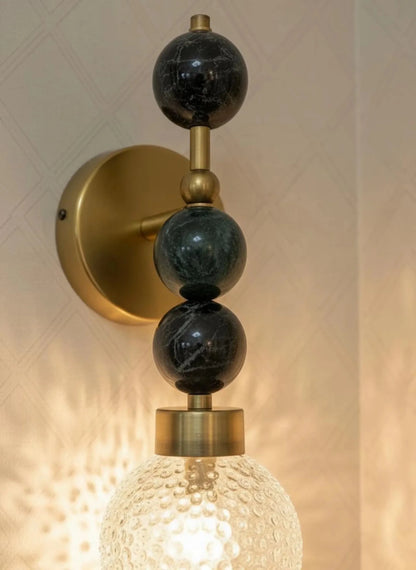 Wall-mounted light fixture with gold and black design on a neutral background
