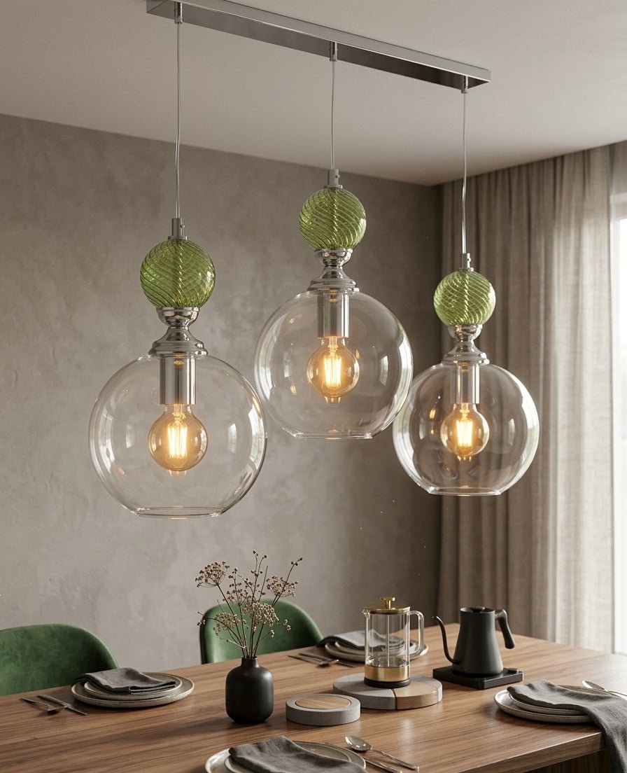 Modern pendant lights fixture with glass shades and green accents hanging over a dining table - Les Trois Pyramides