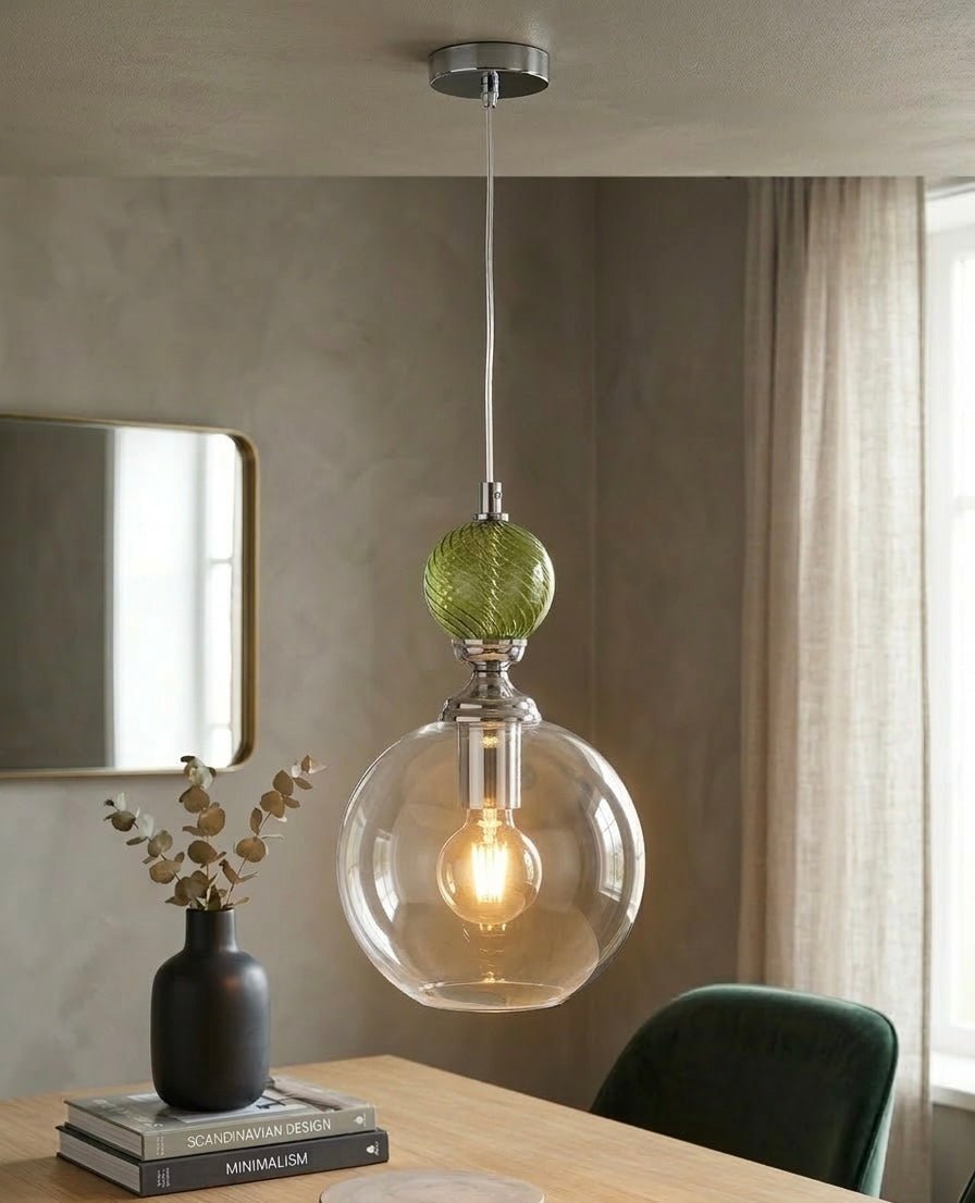 Modern pendant light with a green glass orb and clear glass shade hanging above a table - Les Trois Pyramides