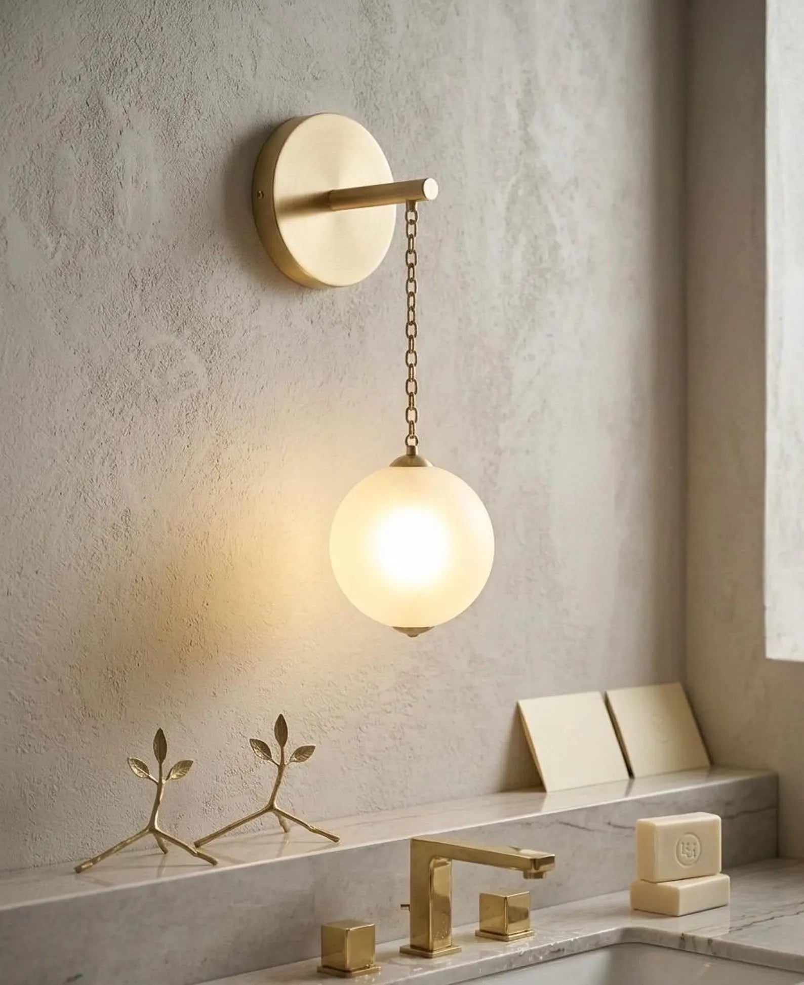 Modern bathroom light fixture with a round glass shade in a neutral-toned bathroom.
