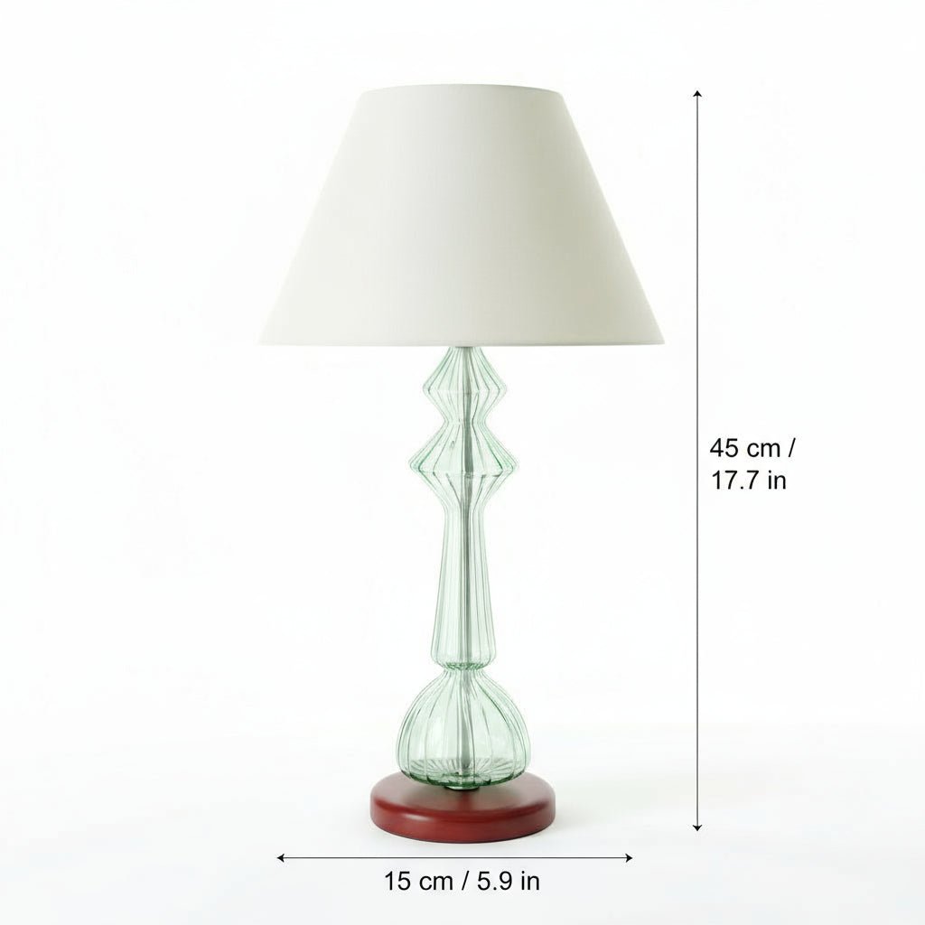 Table lamp with a green glass base and white shade on a white background