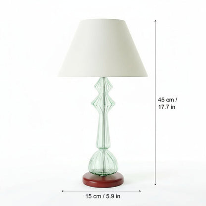Table lamp with a green glass base and white shade on a white background